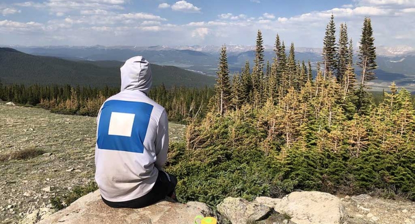 a gap year students sits on a rock overlooking a mountain landscape on an outward bound expedition 